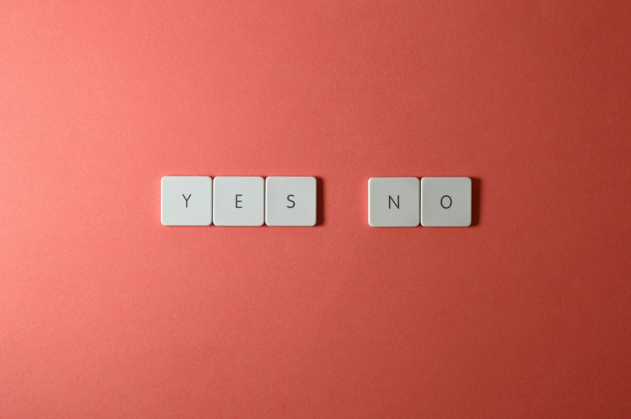 A conceptual image featuring 'yes' and 'no' text on white tiles against a red background, perfect for decision-making themes.