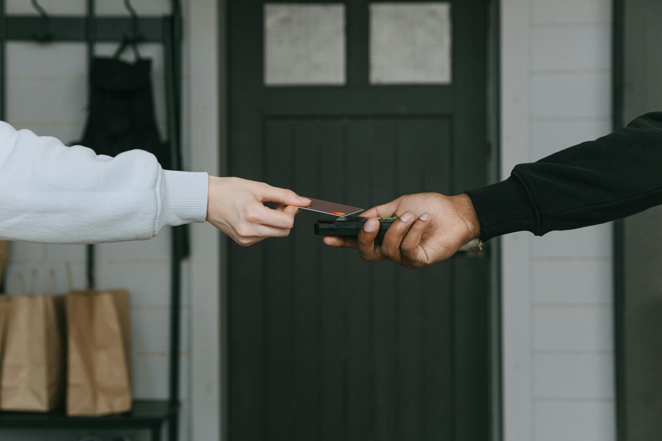 Close-up of hands making a contactless card payment indoors, highlighting cashless transaction technology.